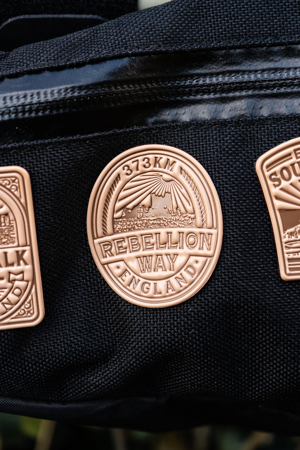 Bikepacking patches flat-lay including Rebellion Way - retro woven cycling route patches