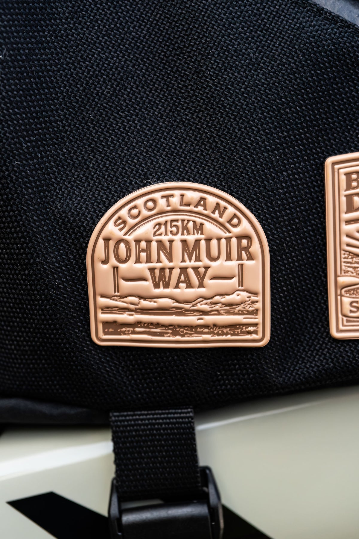 Bikepacking patches flat-lay including John Muir Way - retro woven cycling route patches