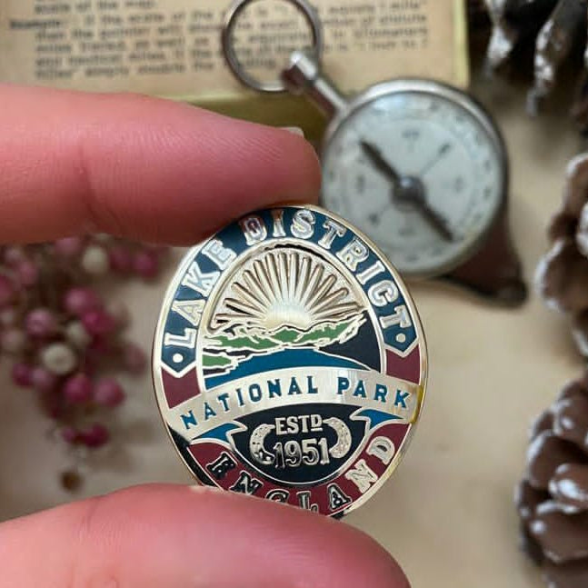 Lake District Heritage pin badge displayed in an outdoor setting – retro enamel badge for fell walkers