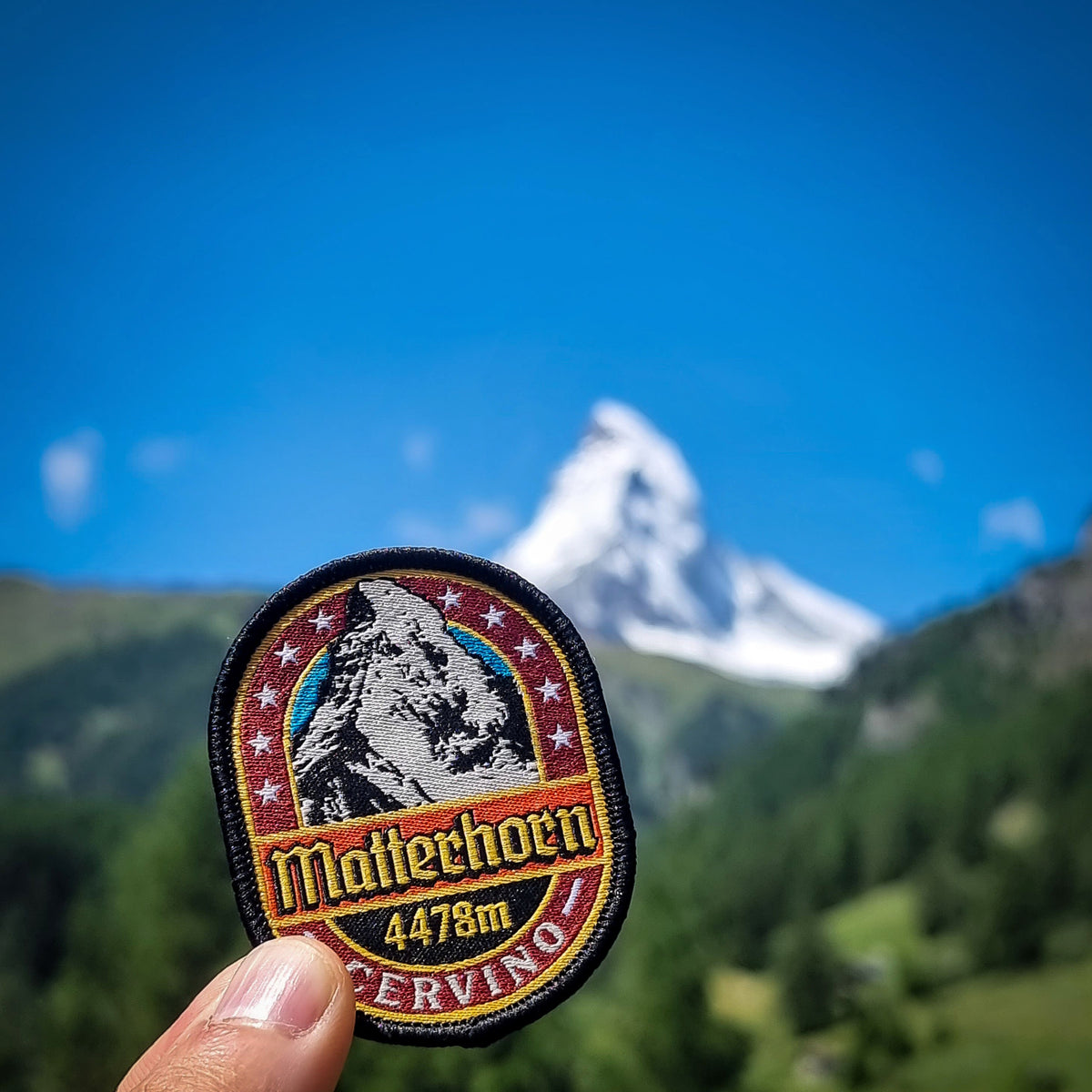 Matterhorn patch in front of the actual Matterhorn – retro woven Alpine patch worn outdoors in Switzerland
