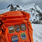 Orange rucksack with Alps patches attached – retro woven Alpine patch collection on outdoor pack