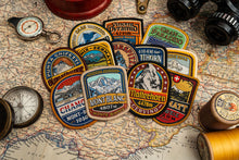 Load image into Gallery viewer, Adventure Patch Company Alps patches hero shot – woven patches on outdoor gear in mountain setting