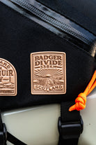 Bikepacking patches flat-lay including Badger Divide - retro woven cycling route patches