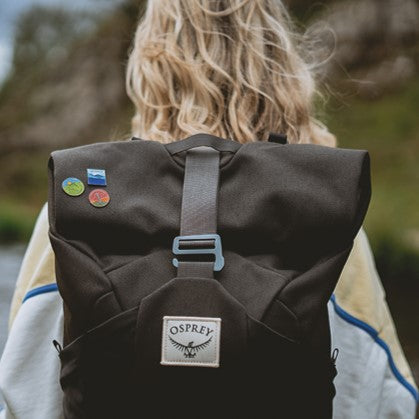 Osprey rucksack with UK National Park enamel pins – female outdoors with pin collection on pack