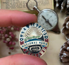 Lake District Heritage pin badge displayed in an outdoor setting – retro enamel badge for fell walkers